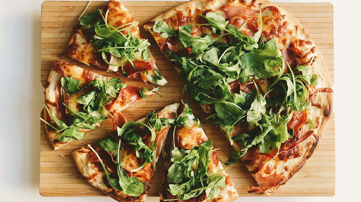 Spinach pizza on wooden cutting board - Foodie Restaurants in Columbus