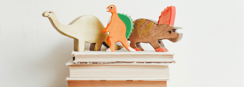 dinosaur figurines on top of stacked books