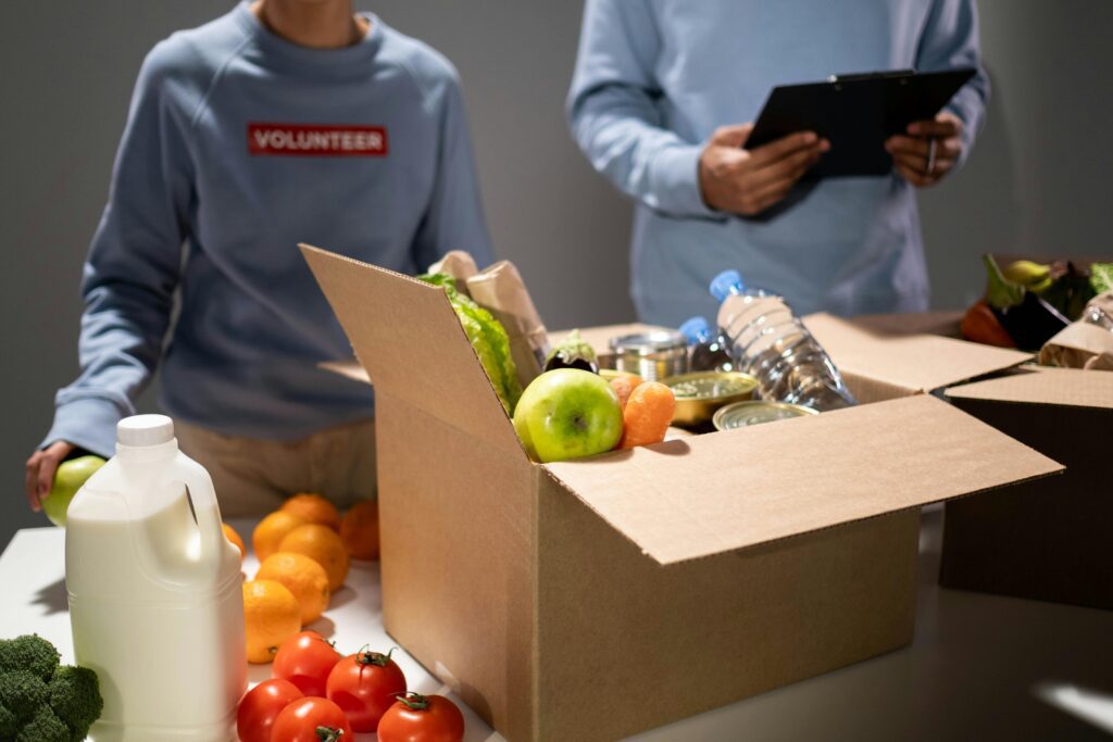 Volunteers standing behind a box of food.