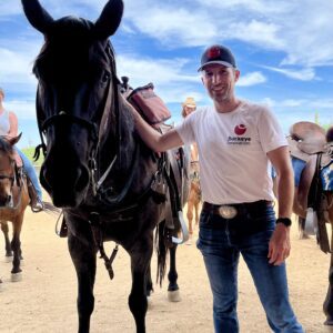 Man in Buckeye Innovation t-shirt and hat standing next to a horse