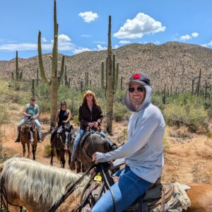 Four people on horseback with mountains and cacti in the background